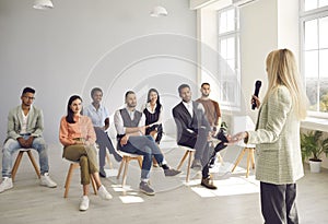 Lady business coach conducts a presentation, trains a team for a multi-racial group of young people