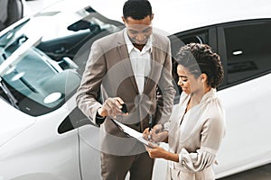 Lady Buying Car Signing Papers With Dealer In Dealership Store