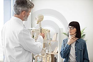 Lady in C collar visiting doctor in clinic for consultation