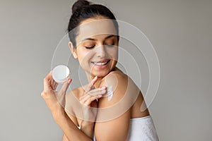 Lady Caring For Skin Applying Moisturizer On Shoulder, Gray Background