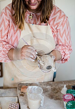 Lady ceramic artist working in her studio interior, woman`s hands painting objects