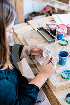 Lady ceramic artist working in her studio interior, woman`s hands painting objects