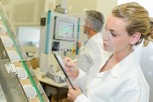 Lady with clipboard inspecting row beakers