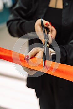 Lady cuts a red ribbon with scissors at the opening ceremony