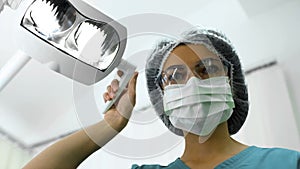 Lady dentist adjusting operatory lights, preparation for surgery, patient POV