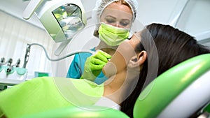 Lady dentist curing female patient tooth, health of oral cavity, modern clinic