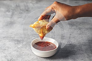 a lady dipping Samosa on tomato sauce. Indian street food.