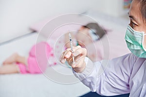 Lady doctor preparing an injection for a little asian girl