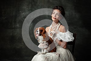 Lady with dog. Vintage portrait of young elegant woman in image of medieval person in renaissance style dress 