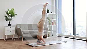 Lady doing yoga exercises in tight leggings and top in front of french windows.