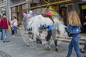 Lady dressed like angel riding on the roller skates at the street