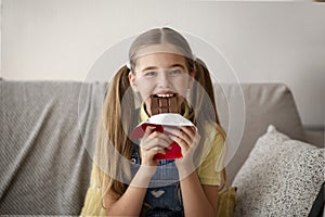 Lady eating chocolate sitting on a couch at home