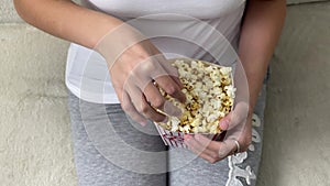 Lady eating popcorn while looking at TV screen