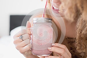 Lady enjoying half a strawberry smoothie jar