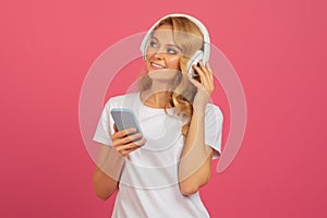 lady enjoying music on smartphone with earphones over pink backdrop