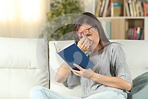 Lady with eyeglasses suffering eyestrain reading a book photo