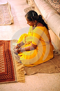A lady finishes a carpet by hand. Jaipur, India.