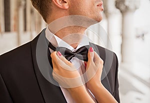 Lady fixing man's bow tie