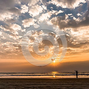 Lady flying a kite on the sunset on Goa beach