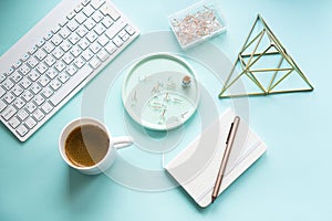 Lady freelancer's home pastel blue workplace, cup of coffee and computer keyboard on tabletop
