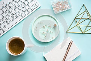 Lady freelancer's home pastel blue workplace, cup of coffee and computer keyboard on tabletop