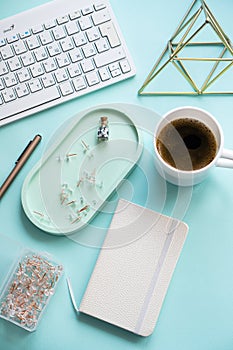 Lady freelancer's home pastel blue workplace, cup of coffee and computer keyboard on tabletop