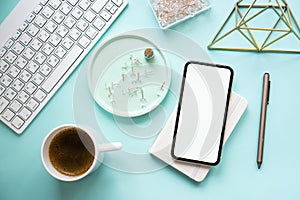 Lady freelancer's home pastel blue workplace, cup of coffee and smartphone mock-up on tabletop