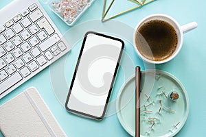 Lady freelancer's home pastel blue workplace, cup of coffee and smartphone mock-up on tabletop