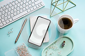 Lady freelancer's home pastel blue workplace, cup of coffee and smartphone mock-up on tabletop