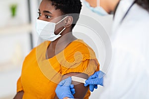 Lady Getting Vaccinated While Doctor Applying Plaster After Injection Indoors