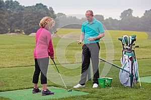 Lady golfer being taught by a golf pro.