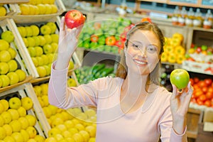 Lady in grocers holding two apples different varieties photo