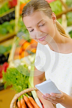 Lady in grocers looking at shopping list photo