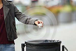 Lady hand throwing garbage to a trash bin photo