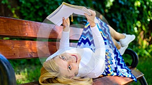 Lady happy face enjoy reading. Girl lay bench park relaxing with book, green nature background. Woman spend leisure with