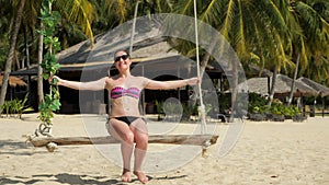 Lady has rest swinging against tropical bungalows and nature