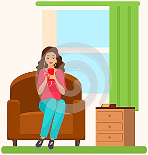 Lady in headpones sitting on couch, listening to music and browsing social media on smartphone