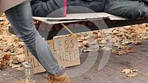 Lady helping poor homeless man by throwing dollars in can, charity, poverty