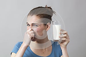 Lady holding a glass of milk and pinching her nose