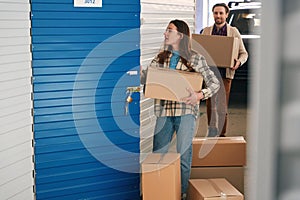 Young woman and man with big cardboard boxes into warehouse