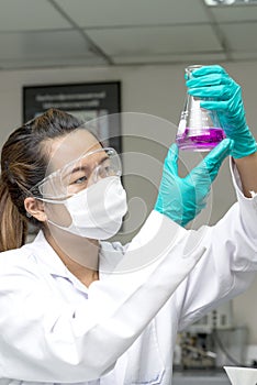 Lady holding and looking at chemical in test glass