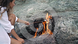 Lady holds marshmallow stick over Chimaera mountain fire