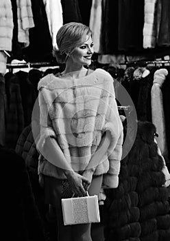 Lady holds white bag in fur shop. Winter clothing concept.