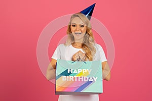 lady joyfully holds her birthday gift against pink studio backdrop