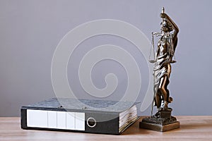 Lady justice or justitia statue and file folder on desk