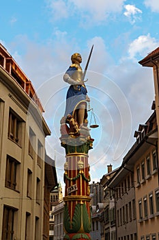 The lady justice statue with raised sword between buildings in Lausanne