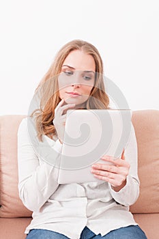 Lady laying on couch being pensive looking on tablet