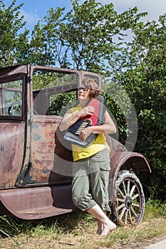 Lady leaning against vintage car playing her harp
