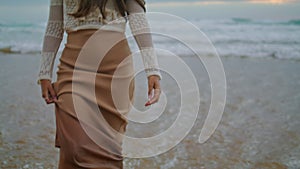 Lady legs going ocean waves closeup. Romantic woman touching long hair at sea