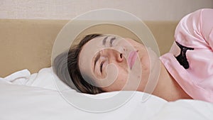 Lady lies in bed closing ear with pillow